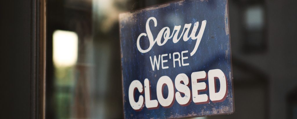Photo of a "Sorry Closed" sign hanging in window