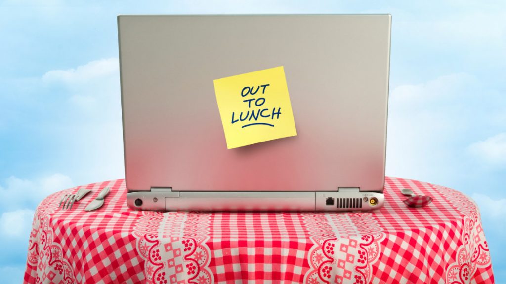 Post it note on a laptop that reads out to lunch for article about lunch breaks