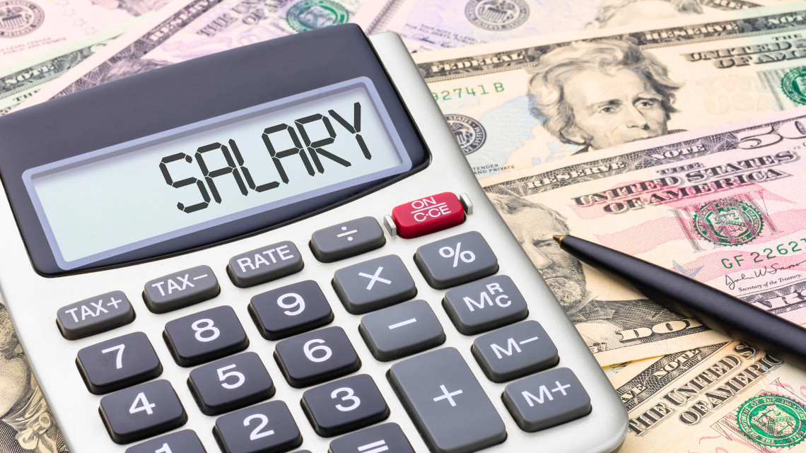 Calculator with the word salary on it, sitting on a background of money