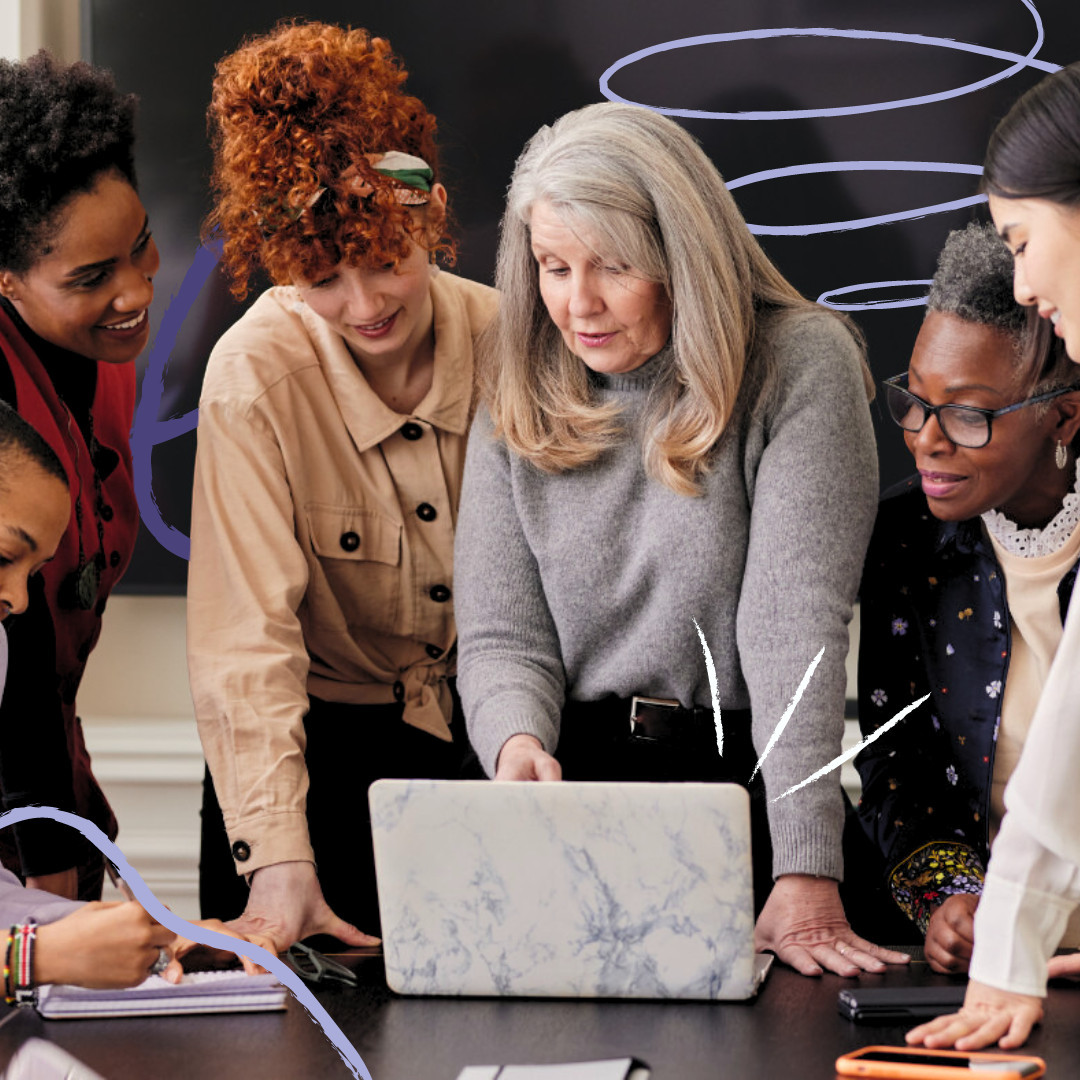 Women gather around a laptop