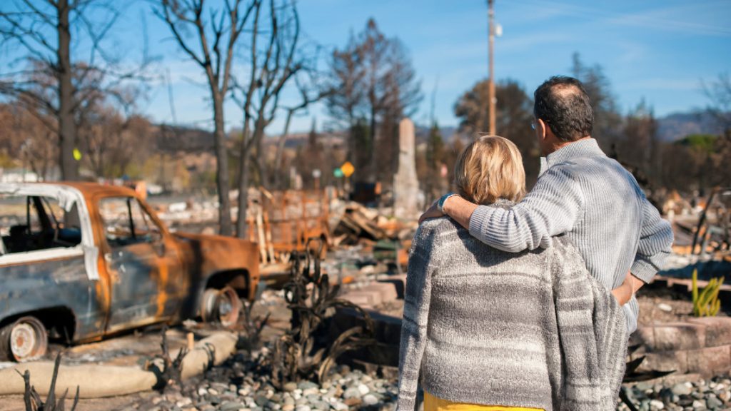 Two people standing in the aftermath of natural disasters