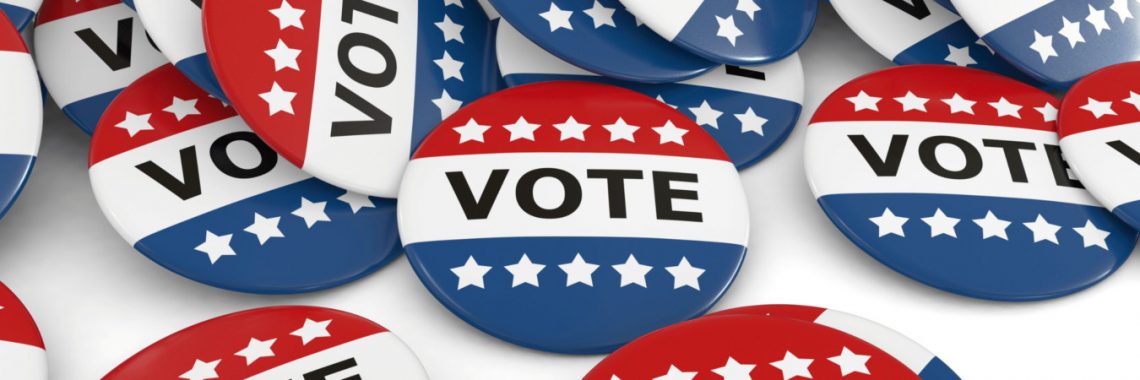 A pile of red, white, and blue "VOTE" buttons with stars for a political campaign.