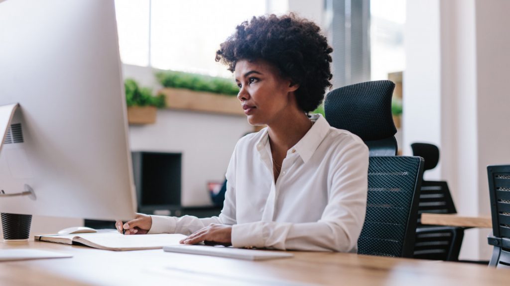 a woman sits at her desk in front of a computer