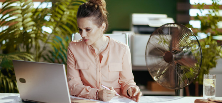 A woman sits at a laptop looking concerned.