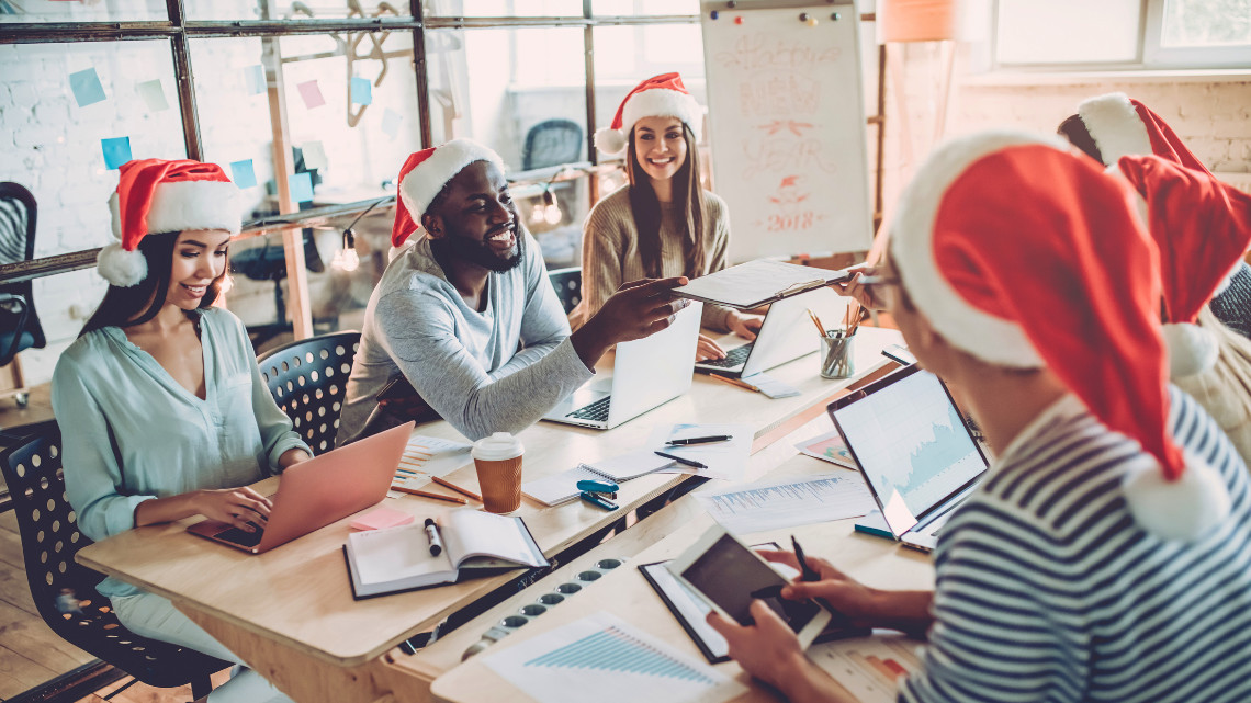 co-workers surrounding a desk to celebrate the holidays