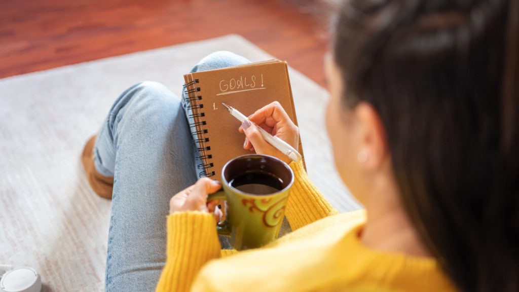 person writing goals and resolutions in a notebook