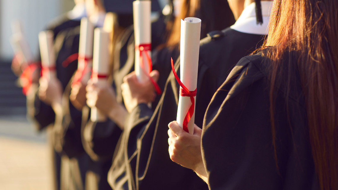 Row of graduates holding diplomas for article on starting salaries