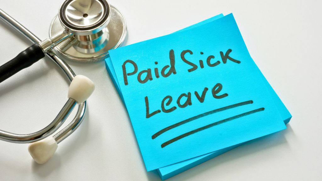 the words 'paid sick leave' written on a post-it sitting next to a stethoscope